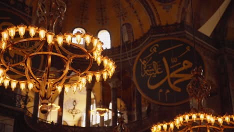 Old-Chandeliers-And-Islamic-Calligraphy-Inside-The-Hagia-Sophia-Grand-Mosque-In-Istanbul,-Turkey