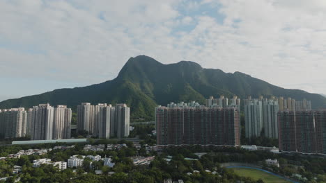 Drone-view-of-skyscrapers-with-mountains-in-the-background-in-Hong-Kong,-China