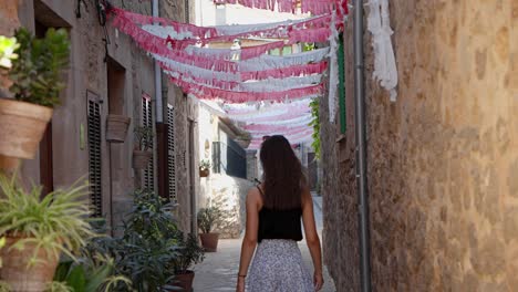 Beautiful-women-going-down-a-decorated-sidewalk-on-a-sunny-day-in-valldemossa,-highest-village-at-mallorca