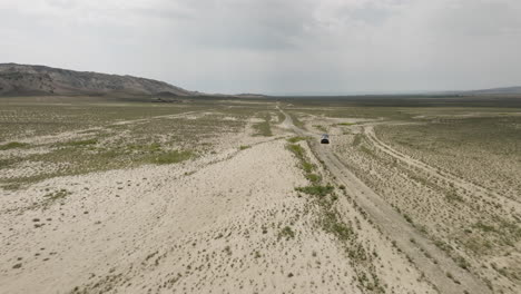 Jeep-driving-on-dirt-road-in-vast-arid-steppe-plain-in-Georgia