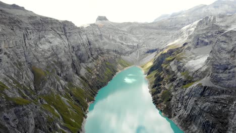 Eine-Umgekehrte-überführung-über-Einen-Wanderer,-Der-Den-Blick-Auf-Den-Limmernsee-In-Glarus,-Schweiz,-Genießt,-Dessen-Türkisfarbenes-Wasser-Von-Hohen-Schweizer-Alpengipfeln-Und-Klippen-Umgeben-Ist