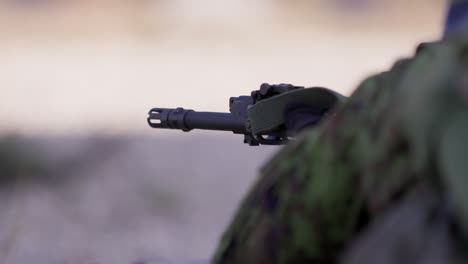 Soldier-firing-assault-rifle,-rifle-barrel-in-closeup
