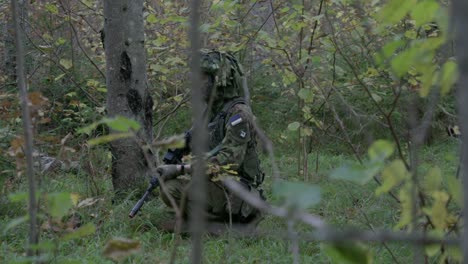 Soldier-in-camouflage-kneel,-stalking-in-forest,-slow-motion,-handheld