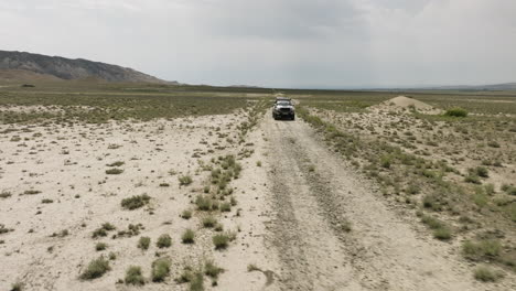 Jeep-standing-on-dirt-road-in-arid-steppe-plain-in-Vashlovani,-Georgia