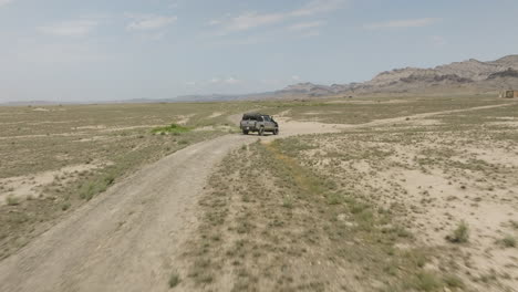 Jeep-driving-slowly-on-sandy-dirt-road-in-arid-steppe-in-Georgia