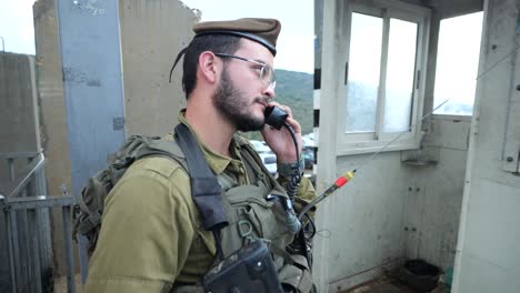 heavily-armed-IDF-soldier-using-handheld-radio-in-security-checkpoint