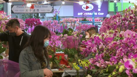 Chinese-shoppers-buy-decorative-Chinese-New-Year-theme-flowers-and-plants,-such-as-orchids,-at-a-flower-market-street-stall-ahead-of-the-Lunar-Chinese-New-Year-festivities