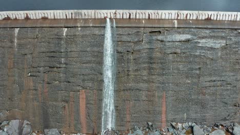 Aerial,-small-waterfall-flowing-down-reservoir-dam