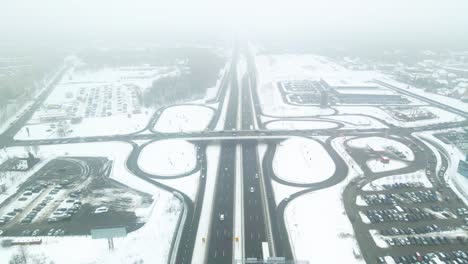 drone-shot-of-interchange-roads-in-Kaunas,-Lithuania,-everything-covered-with-snow-in-cold-fogy-cloudy-winter
