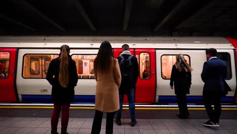 Toma-De-Un-Tren-Que-Llega-A-Una-Estación-De-Metro-Llena-De-Gente-Esperando-En-Londres,-Reino-Unido