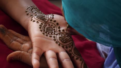 A-close-up-shot-of-a-black-woman-hand-being-painted-with-henna
