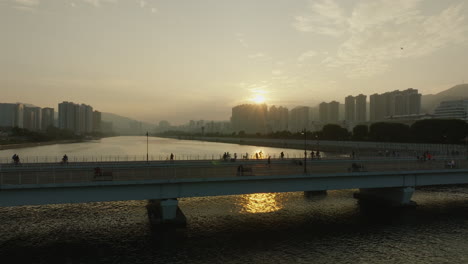 Hong-Kong-In-Surnet-Luftaufnahme-Der-Wolkenkratzer-Skyline-Stadtbild-Modernes-Gebäude-Mit-Fußgängerchinesen,-Die-Zu-Goldenen-Stunden-über-Die-Brücke-Gehen