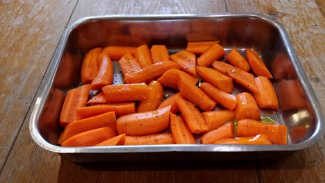 Aceite-Rociado-Sobre-Zanahorias-Peladas,-Cortadas-Y-Sazonadas-Listas-Para-Asar