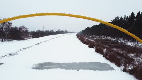 Drohnenvideo-Einer-Gelben-Brücke-Auf-Einem-Zugefrorenen-Fluss-Im-Wald-In-Warschau