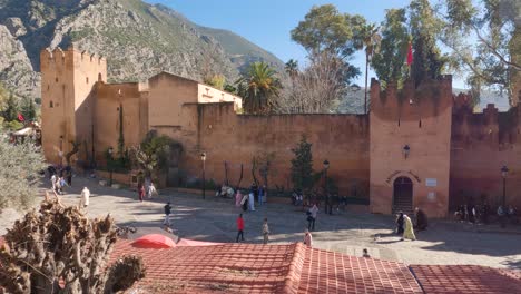 People-walking-outside-the-historic-kasbah,-fort,-of-Chefchaouen,-Morocco