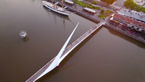 Orbiting-over-Puente-de-la-Mujer-in-Puerto-Madero,-Modern-Pedestrian-rotating-bridge,-Buenos-Aires
