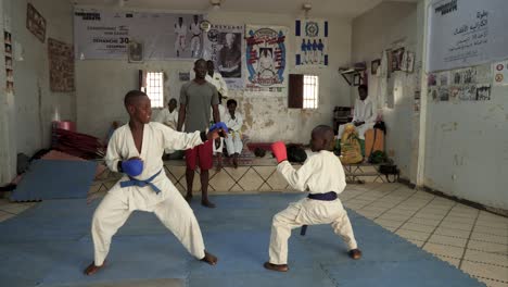 Zwei-Afrikanische-Kinder-Mit-Trainingshandschuhen-Kämpfen-In-Einem-Dojo