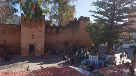 View-Overlooking-People-Walking-Past-The-Kasbah,-Place-Outa-El-Hamam,-Located-At-Chefchaouen,-Morocco