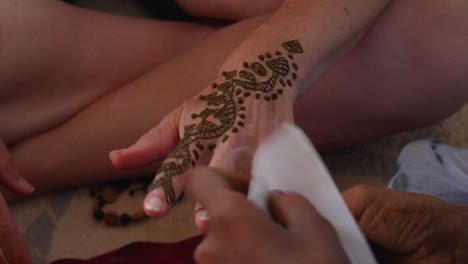 A-close-up-shot-of-a-white-woman-hand-being-painted-with-henna