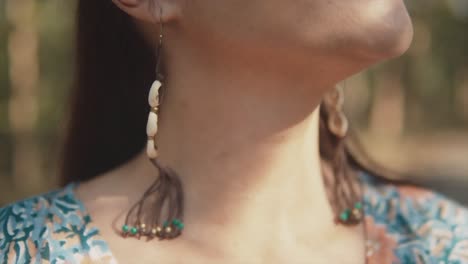 Up-Close-slow-shot-of-a-young-woman's-upper-body-in-a-blue-dress-and-earrings