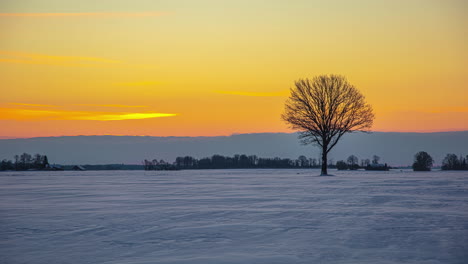 Beautiful-sunset-sky-through-frozen-field,-moving-clouds-at-the-background,-Timelapse