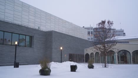 People-Walking-Past-Square-Beside-The-National-Museum-of-Art,-Architecture,-and-Design-And-Nobel-Peace-Center-During-Winter-Snow-Fall