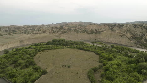 Meandering-Alazani-river-flowing-around-circular-peninsula-with-trees