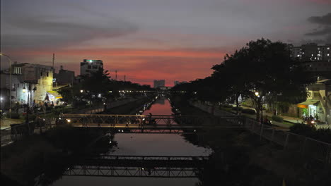 Small-bridge-over-river-in-city-at-sunset