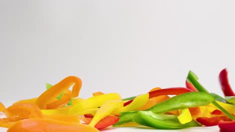 Bright-colorful-bell-pepper-vegetable-medley-falling-and-bouncing-into-a-pile-on-white-table-top-in-slow-motion