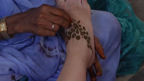 Eine-Aufnahme-Der-Hände-Einer-Schwarzen-Frau,-Die-Den-Fuß-Einer-Weißen-Frau-Mit-Henna-Bemalt