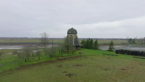 Beautiful-aerial-establishing-view-of-old-wooden-windmill-in-the-middle-of-the-field,-Prenclavu-windmill-,-overcast-winter-day,-wide-drone-shot-moving-forward