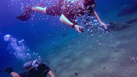 People-scuba-diving-near-the-ocean-floor-and-making-air-bubbles