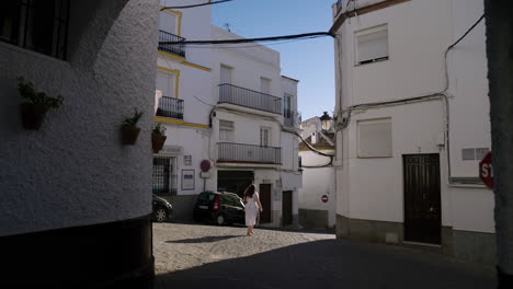 Girl-In-White-Dress-Walking-Through-Empty-Street-Of-Olvera,-Spain