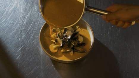 Chef-pours-sauce-on-shellfish-foodplate