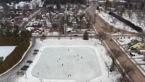 Aerial,-people-ice-skating-on-neighborhood-community-ice-rink