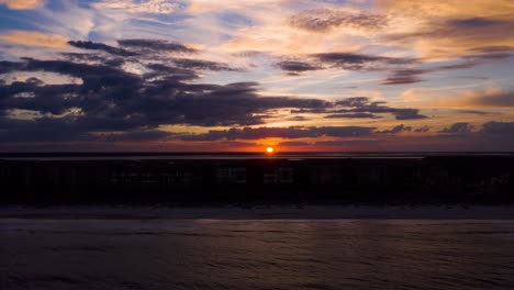 Aerial-sunset-hyperlapse-at-an-ocean-beach-with-dramatic-clouds