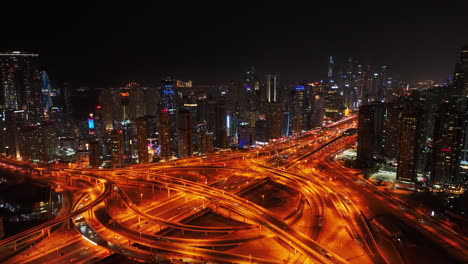 Aerial-descending-footage-of-vehicles-passing-through-large-highway-interchange-in-night-city