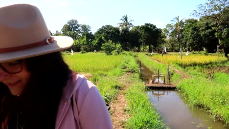 Tourist-woman-walks-with-a-camera-in-a-cultivated-area-next-to-an-irrigation-canal-in-Mto-wa-Mbu