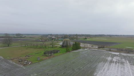 Beautiful-aerial-establishing-view-of-old-wooden-windmill-in-the-middle-of-the-field,-Prenclavu-windmill-,-overcast-winter-day,-wide-drone-shot-moving-forward