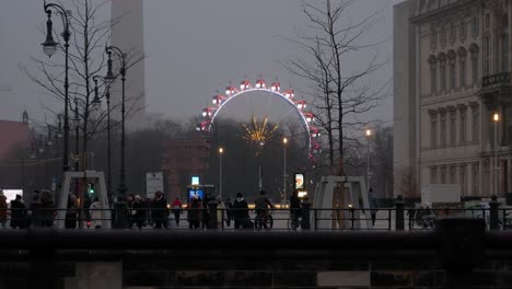 Ferris-wheel-of-Berlin-glowing-and-spinning-on-moody-evening,-distance-view