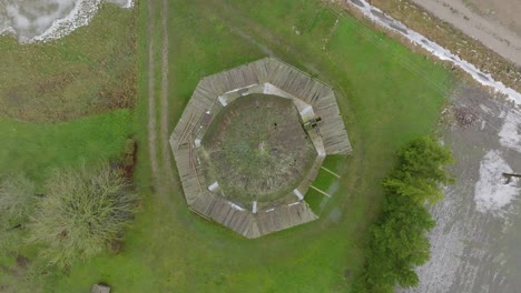 Beautiful-aerial-establishing-view-of-old-wooden-windmill-in-the-middle-of-the-field,-Prenclavu-windmill-,-overcast-winter-day,-descending-birdseye-point-of-interest-drone-shot