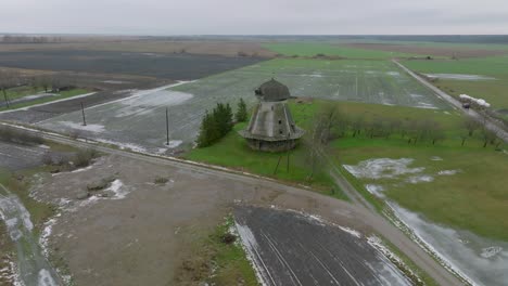 Beautiful-aerial-establishing-view-of-old-wooden-windmill-in-the-middle-of-the-field,-Prenclavu-windmill-,-overcast-winter-day,-wide-drone-shot-moving-forward,-tilt-down