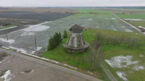 Beautiful-aerial-establishing-view-of-old-wooden-windmill-in-the-middle-of-the-field,-Prenclavu-windmill-,-overcast-winter-day,-wide-drone-shot-moving-backward,-tilt-up