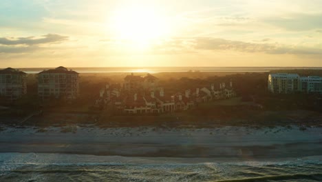 Aerial,-luxurious-beachside-vacation-villas-on-an-island-during-sunset