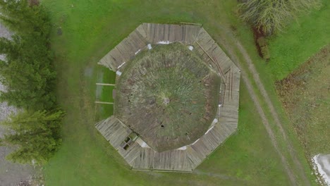 Beautiful-aerial-establishing-view-of-old-wooden-windmill-in-the-middle-of-the-field,-Prenclavu-windmill-,-overcast-winter-day,-ascending-wide-birdseye-drone-shot