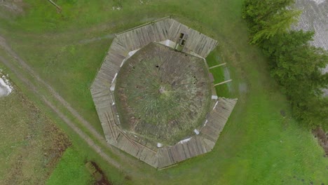 Beautiful-aerial-establishing-view-of-old-wooden-windmill-in-the-middle-of-the-field,-Prenclavu-windmill-,-overcast-winter-day,-ascending-birdseye-drone-shot