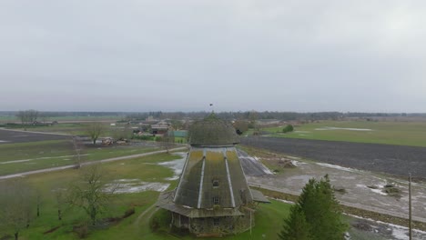 Beautiful-aerial-establishing-view-of-old-wooden-windmill-in-the-middle-of-the-field,-Prenclavu-windmill-,-overcast-winter-day,-wide-drone-shot-moving-backward