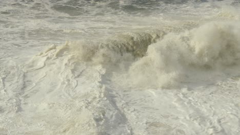 Stormy-rough-sea-water,-small-waves-with-foam,-Nazare-in-Portugal-high-angle-view