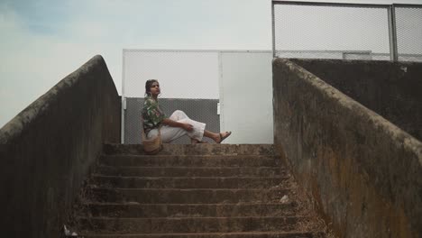 Long-shot-of-a-girl-sitting-on-a-concrete-staircase