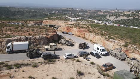 Israel-Army-squad-soldiers-on-Humvee-vehicles-driving-through-training-ground-country-road,-Aerial-Tracking-shot